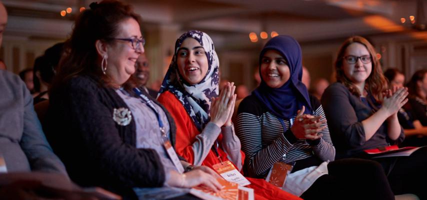 women clapping and celebrating together in event audience