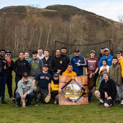 Group shot of the Edinburgh Rays baseball in playing field, standing/crouching around their logo