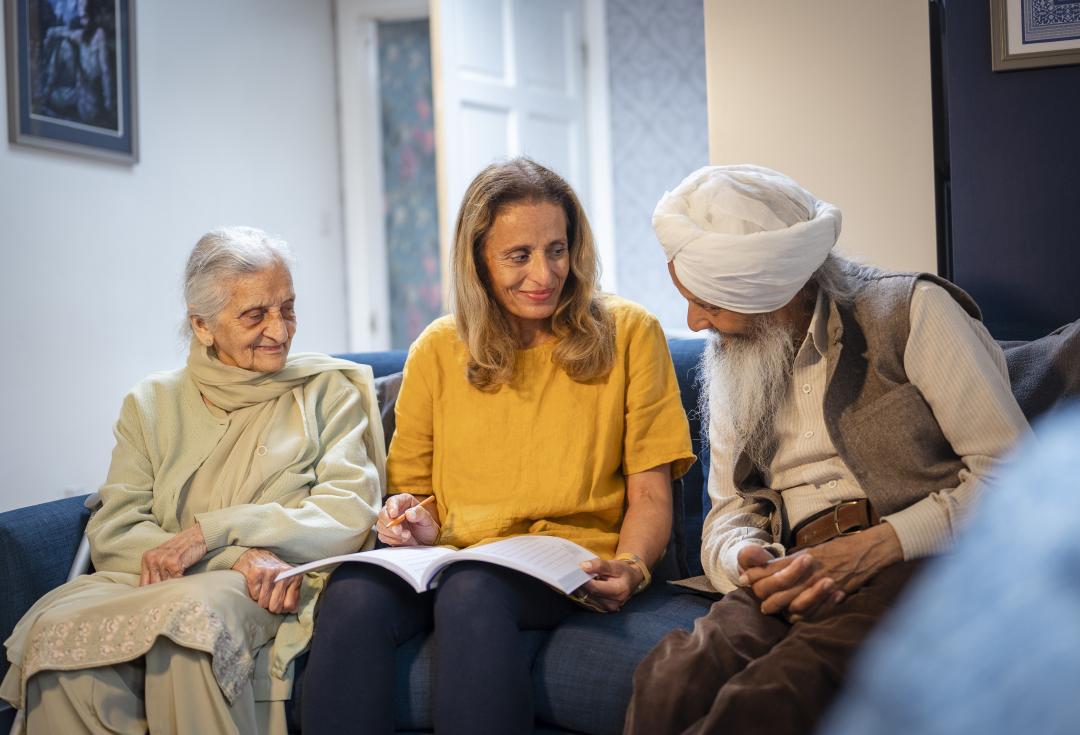 an older man and woman smiling and speaking with a younger woman
