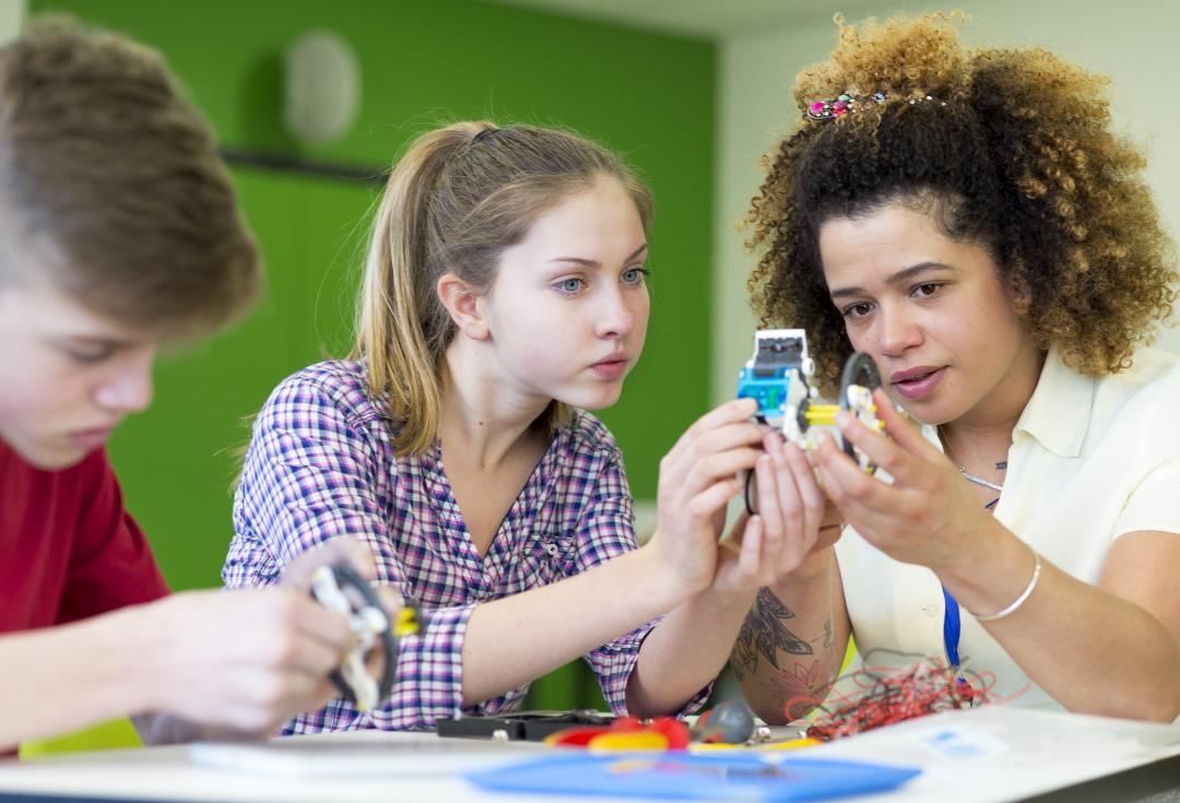 Three young people holding up and looking at circuits