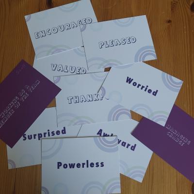 A collection of cards with words that describe feelings for example powerless, encouraged, pleased.