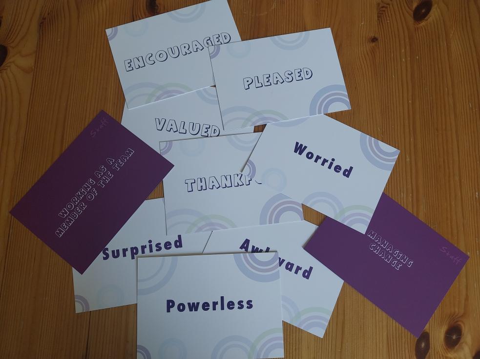 A collection of cards with words that describe feelings for example powerless, encouraged, pleased.