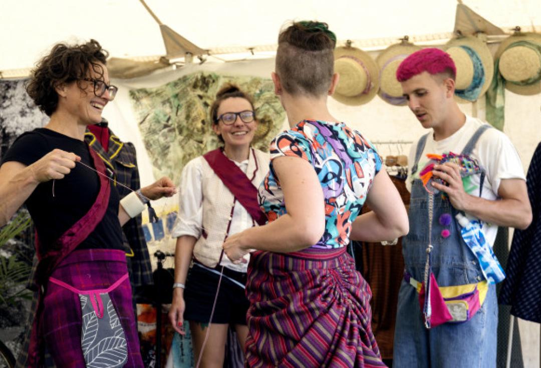 group of 4 people in bright clothes engaging at a festival