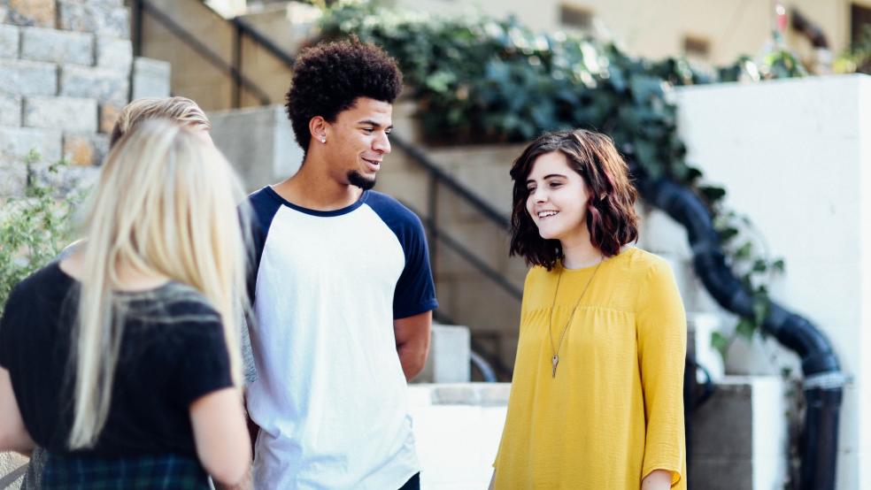 group of 3 young people standing and talking together