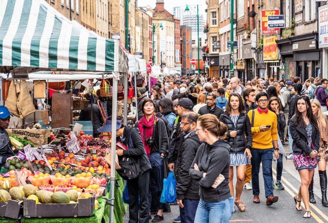 A busy outdoor market with lots of people browsing the stalls