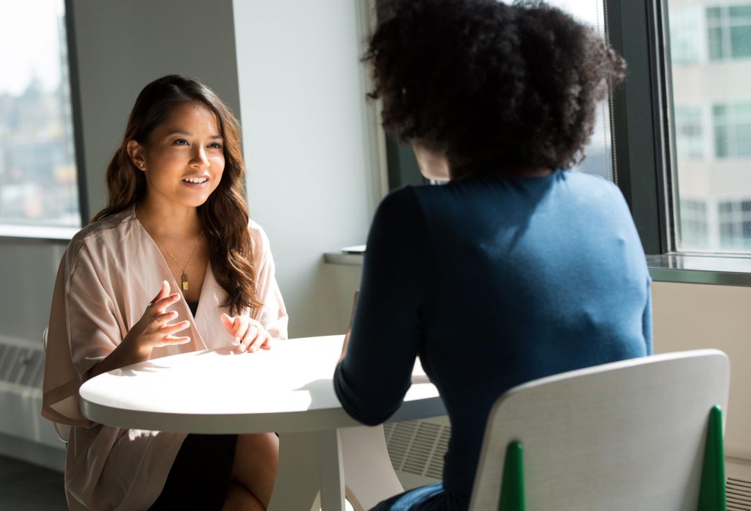 two women talking to each other across a table