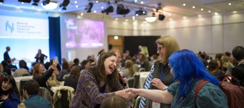 3 people meeting and smiling around a table at Engage conference 