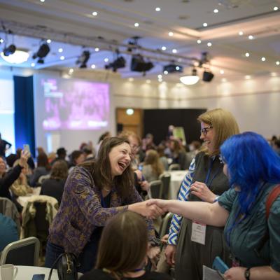 3 people meeting and smiling around a table at Engage conference 