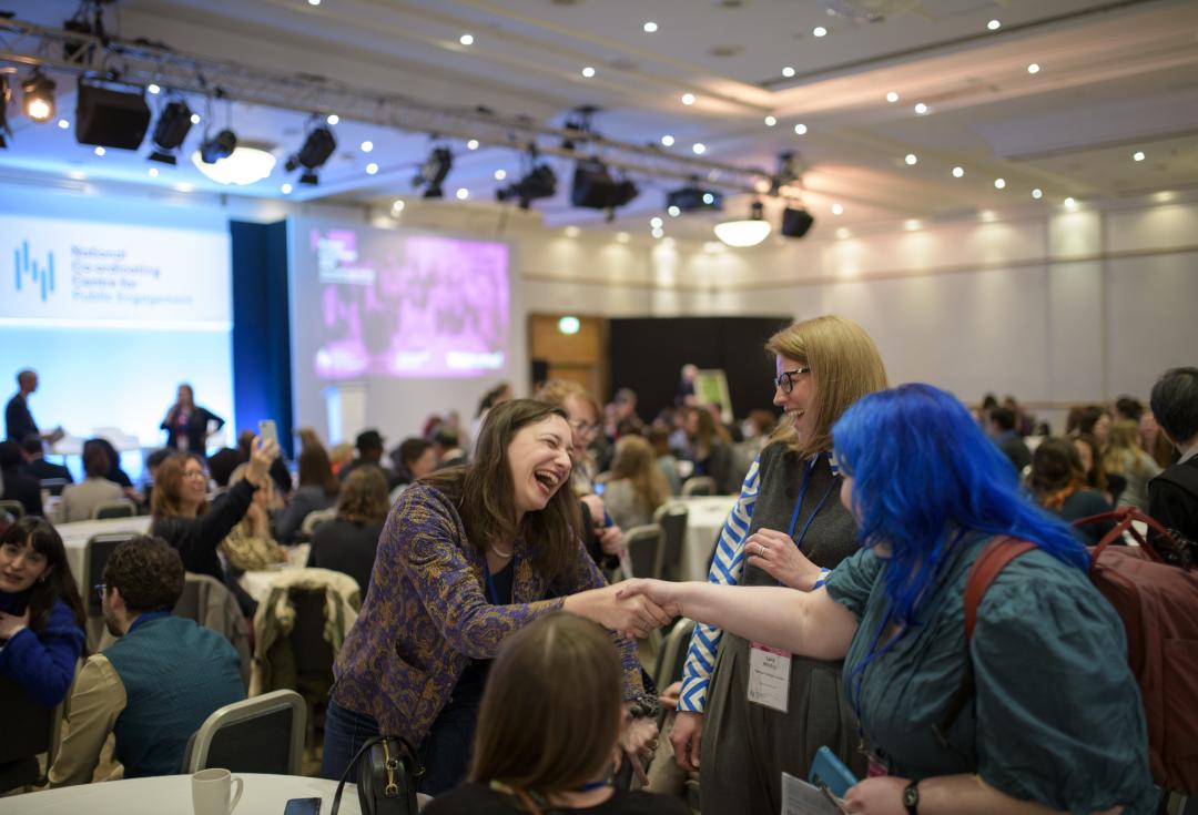3 people meeting and smiling around a table at Engage conference 