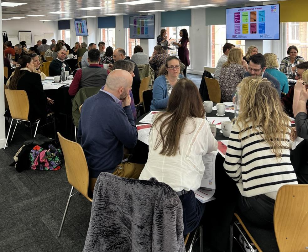 Members of the NCIA action learning groups discussing topics around tables.