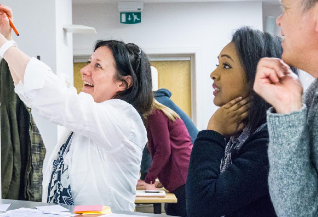 People at a workshop looking up at some notes on the wall and smiling