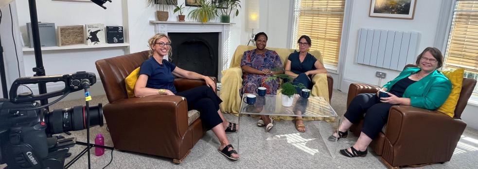 Sophie Duncan, Jude Fransman, Fay Scott, Louise Archer (R-L) sat in armchairs around a coffee table, with filming and sound equipment around them, smiling at the camera